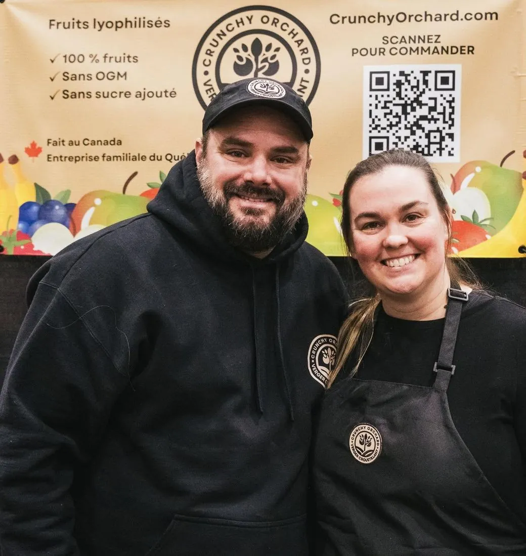 Patrick and Cindy, the couple behind Crunchy Orchard, smiling at their market booth